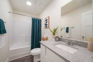 Bathroom featuring a white tub and shower combination, a single vanity with a light-toned countertop, an integrated sink, and wood-finish flooring