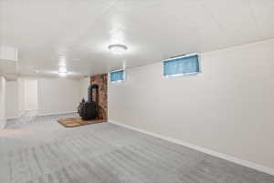 Spacious room featuring a central wood-burning stove with a stone surround, light gray patterned carpeting, and white painted walls