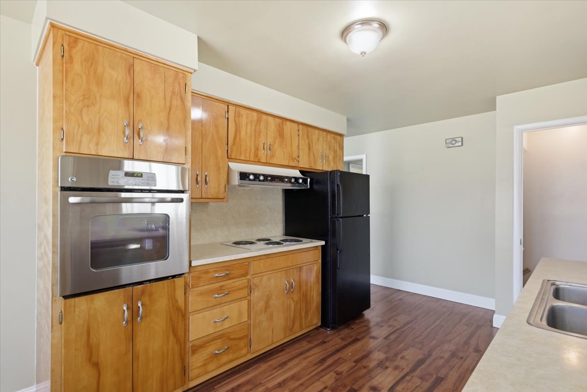 Kitchen featuring wood-finish cabinetry, built-in stainless steel oven, electric cooktop, and laminate countertops