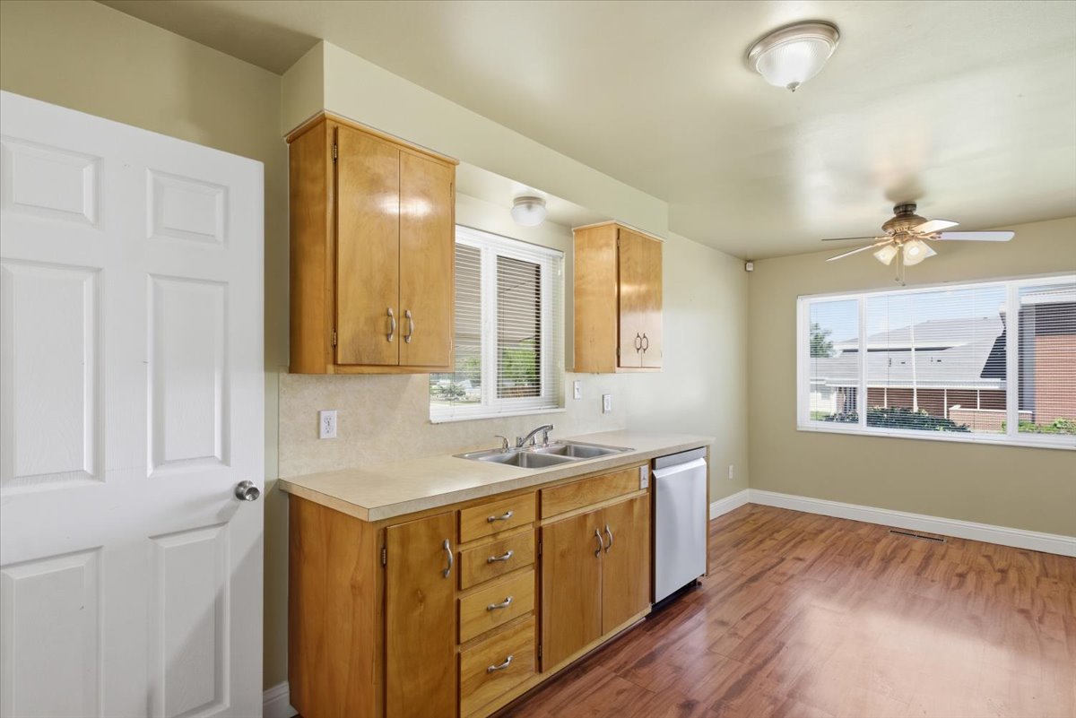 Kitchen featuring wood-finish cabinetry, a double basin sink, and a built-in dishwasher