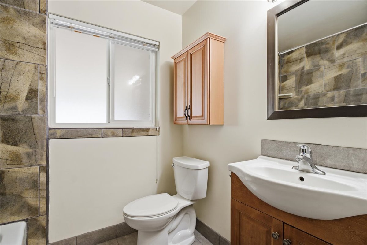 Bathroom featuring a wood-finish vanity with an integrated sink and chrome faucet