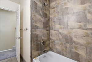 Shower-tub combination featuring large-format tile surround with a textured finish, polished chrome fixtures, and a white porcelain tub