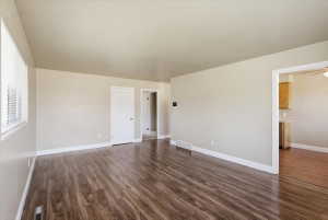 Spacious room featuring wood-finish flooring, light-toned walls, white trim, and window blinds