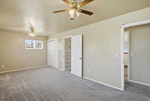 Spacious room featuring neutral wall tones, grey carpeting, two ceiling fans, and bi-fold closet doors