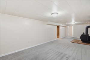Spacious lower-level room featuring light gray carpeting, white walls, and a drop ceiling