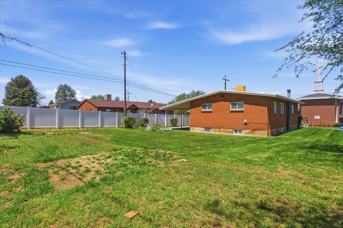 Expansive grassy yard with a white privacy fence