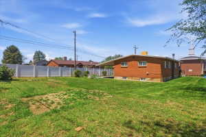 Expansive grassy yard with a white privacy fence