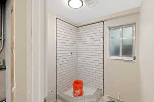 Shower enclosure featuring white subway tile, a corner shower pan, and dark contrasting trim