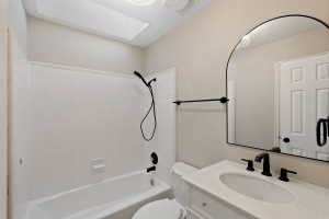 Bathroom featuring a white bathtub with subway tile surround, matte black shower fixtures, a built-in vanity with white cabinetry, a single basin sink, and an arched mirror