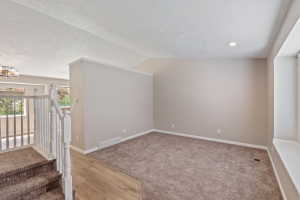 Open concept living space featuring carpeted flooring, light neutral wall tones, white trim accents, a recessed ceiling light, and a window seat