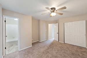 Spacious room featuring neutral carpeting, a ceiling fan with integrated lighting, and light-toned walls