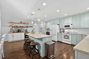 Spacious kitchen featuring wood-finish flooring, a central island with integrated seating, light blue cabinetry, and recessed lighting