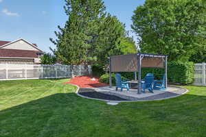 Expansive backyard featuring a lush lawn, a patio area with a pergola, and mature trees