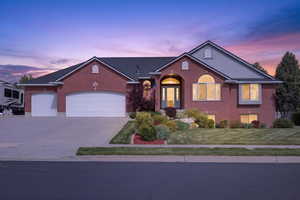 Brick exterior with a multi-car garage, established front landscaping, arched entry, and prominent bay window