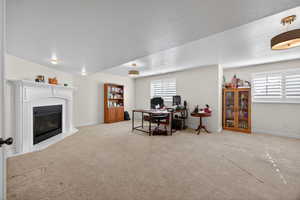 Spacious interior featuring a gas fireplace with a white mantel, light-toned carpeting, recessed lighting, and windows equipped with white plantation shutters