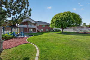 Expansive backyard featuring a lush lawn, mature trees, and a red brick exterior