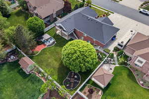 Expansive backyard featuring a large green lawn, mature trees, a dedicated patio area, an additional shed structure, and a tiered stone pathway