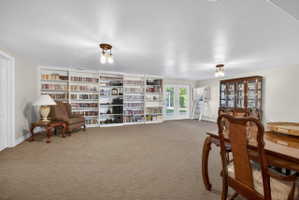 Spacious room with extensive built-in shelving, plush carpet flooring, recessed lighting, and French doors leading to an outdoor area