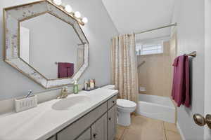 Bathroom featuring a full vanity with an integrated sink, a large octagonal mirror, and a tub-shower combination with tile surround