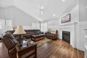 Living area featuring wood-finish flooring, vaulted ceilings, and white paneled wainscoting