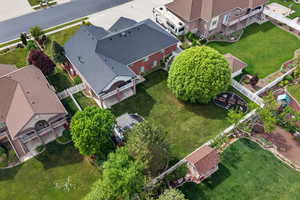 Expansive backyard featuring a manicured lawn, mature trees, a dedicated fire pit area with seating, and a white vinyl fence perimeter