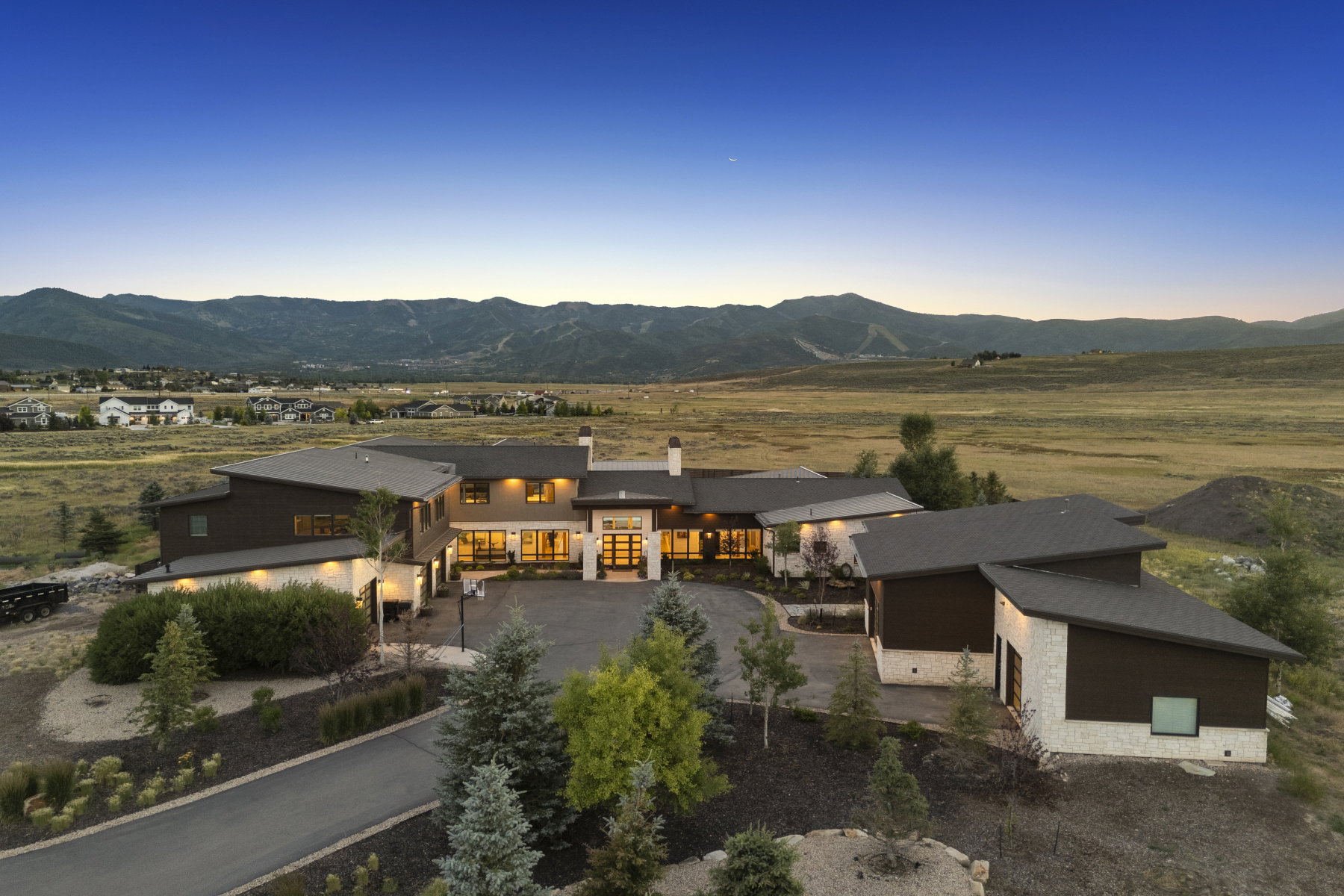 Contemporary architectural design featuring expansive windows, a stone and wood facade, and a multi-level roofline
