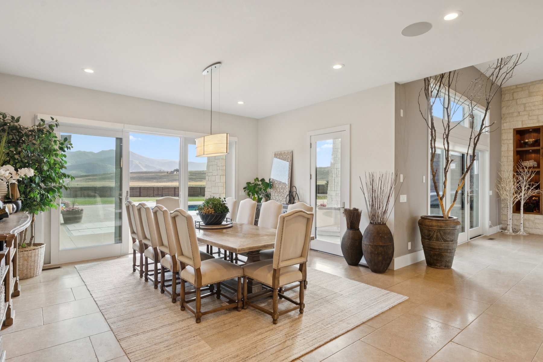 Spacious dining area featuring a rectangular chandelier, recessed lighting, and large format floor tile