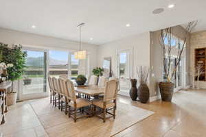 Spacious dining area featuring a rectangular chandelier, recessed lighting, and large format floor tile