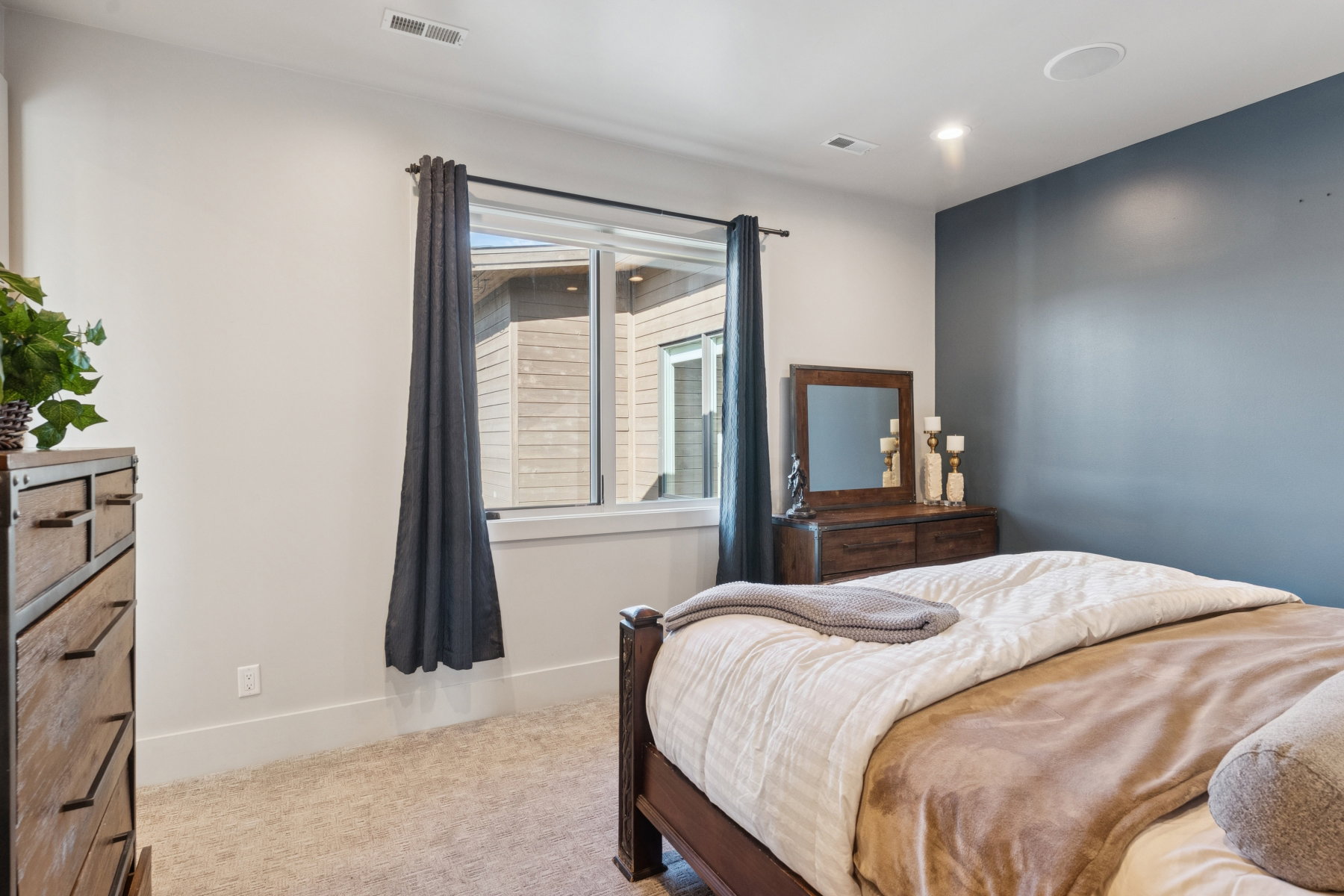 Interior room featuring light-colored carpet flooring, a window with white trim, and a deep blue accent wall
