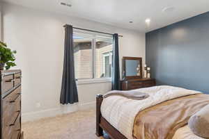 Interior room featuring light-colored carpet flooring, a window with white trim, and a deep blue accent wall