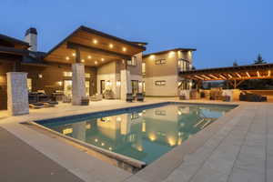 Expansive outdoor living area featuring a large swimming pool, extensive paved patio, and a covered patio with a wood-plank ceiling