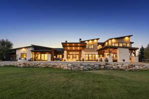 Modern exterior design featuring natural stone accents, extensive glass doors, multiple patios, sloped rooflines, and a covered outdoor living area