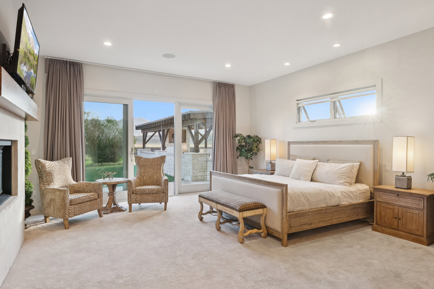 Spacious room featuring light-colored carpeting, recessed lighting, and a large fireplace with a mounted television
