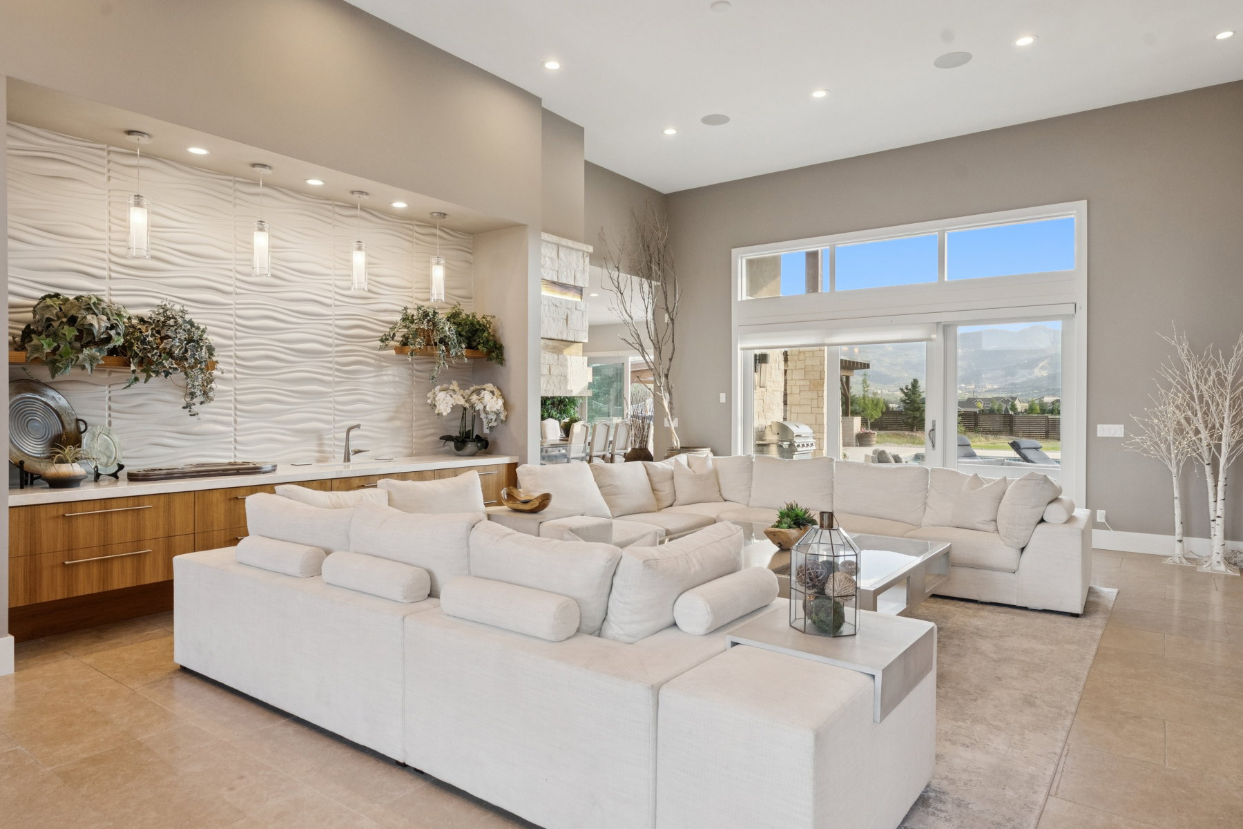 Spacious living area featuring high ceilings, large format tile flooring, and oversized sliding glass doors