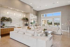 Spacious living area featuring high ceilings, large format tile flooring, and oversized sliding glass doors
