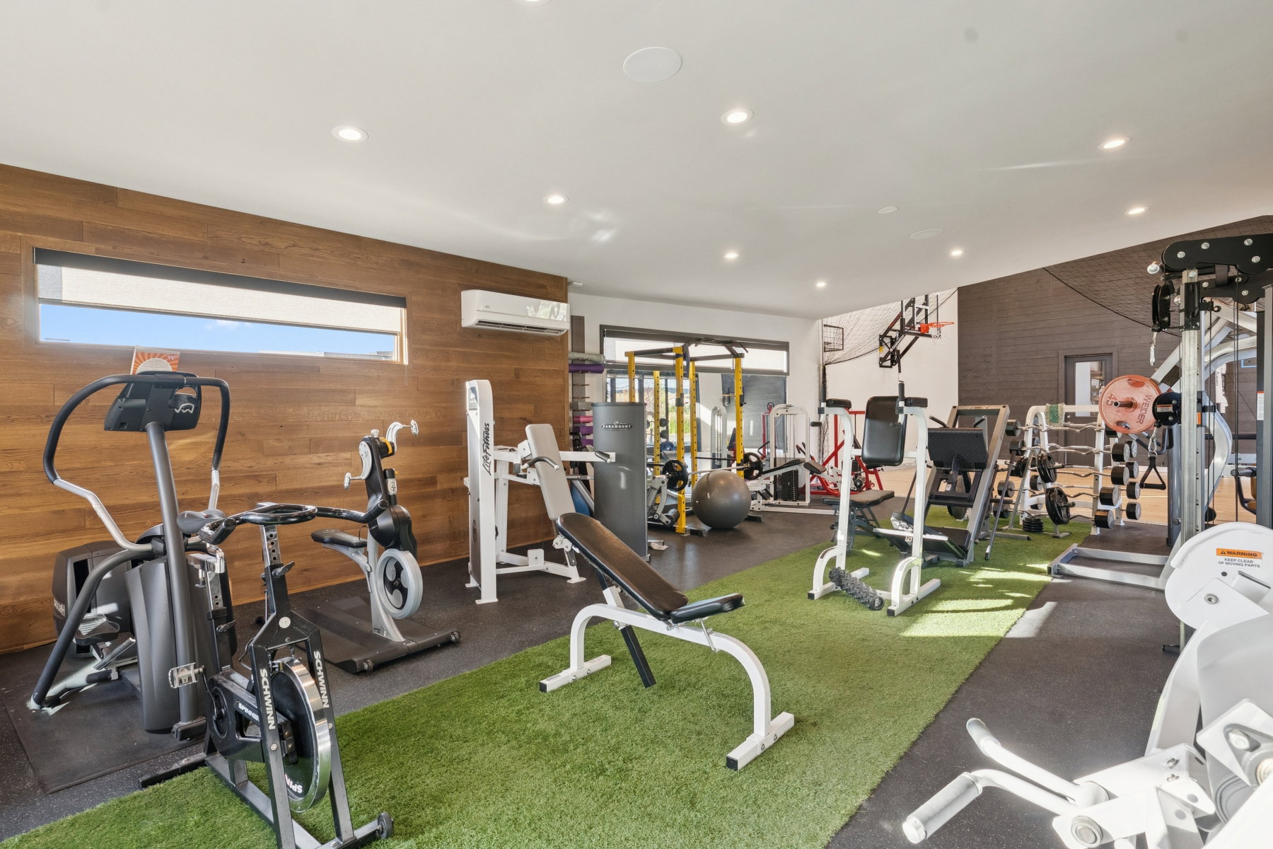 Dedicated fitness space featuring recessed lighting, a wood-finish accent wall, and a horizontal window