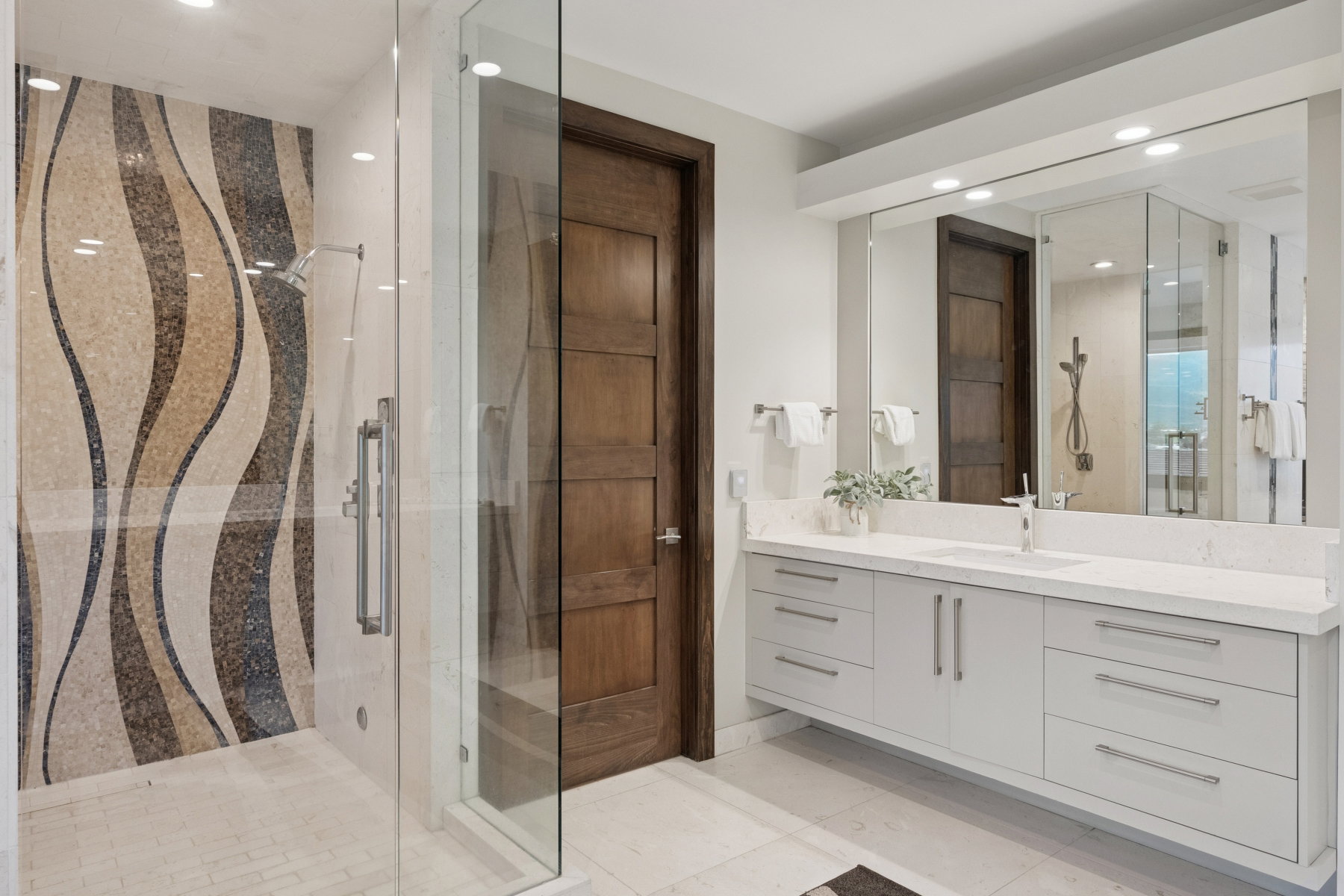 Glass-enclosed shower with a mosaic tile accent wall