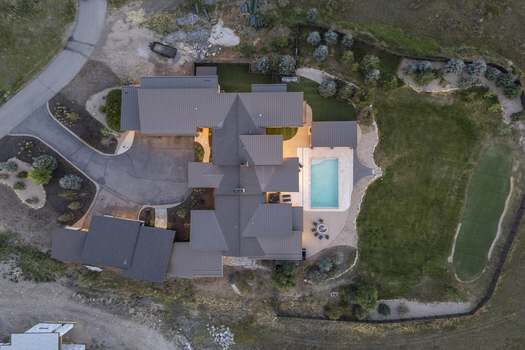 Expansive estate featuring a large swimming pool, paved patio, fire pit area, and a putting green