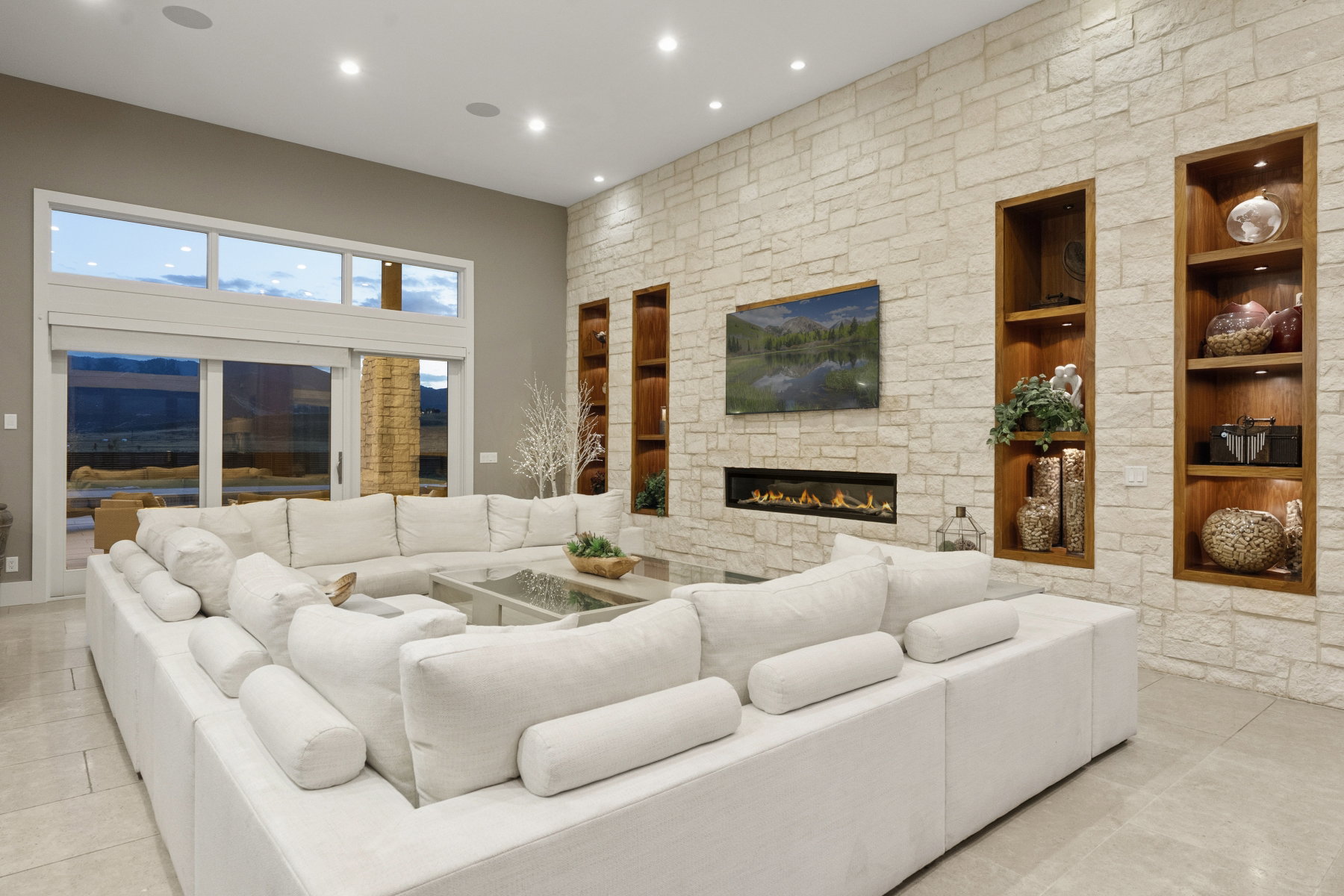 Spacious living area featuring a stone accent wall, recessed lighting, and built-in shelving with integrated illumination