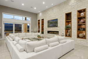 Spacious living area featuring a stone accent wall, recessed lighting, and built-in shelving with integrated illumination