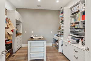 Dedicated room featuring wood-finish flooring, recessed lighting, and a central freestanding island with open shelving