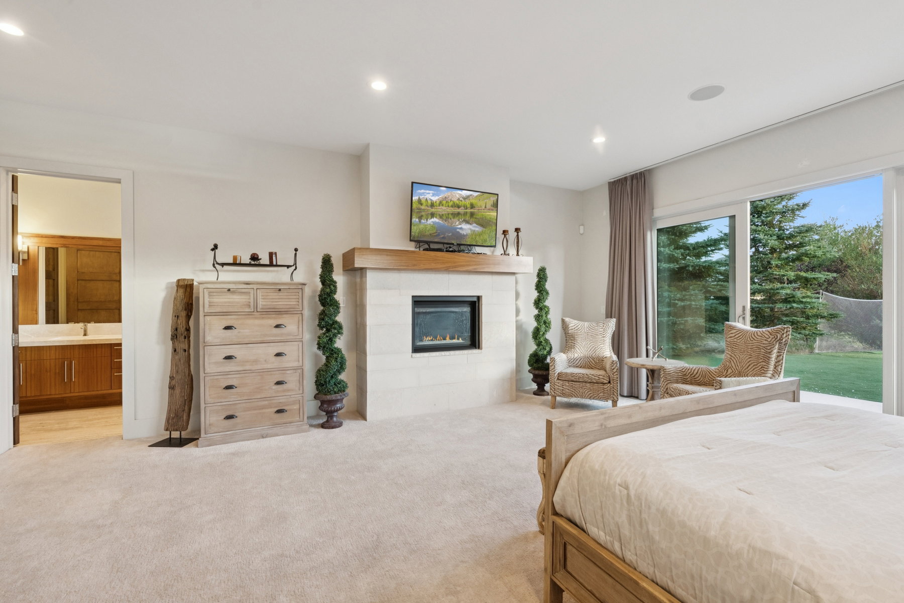 Carpeted room featuring a fireplace with a wood mantle, sliding glass doors, and recessed lighting