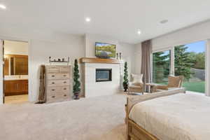 Carpeted room featuring a fireplace with a wood mantle, sliding glass doors, and recessed lighting