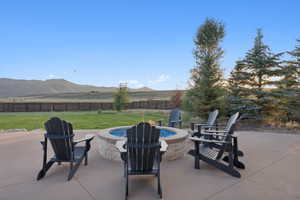 Expansive patio area featuring a built-in stone fire pit with blue fire glass