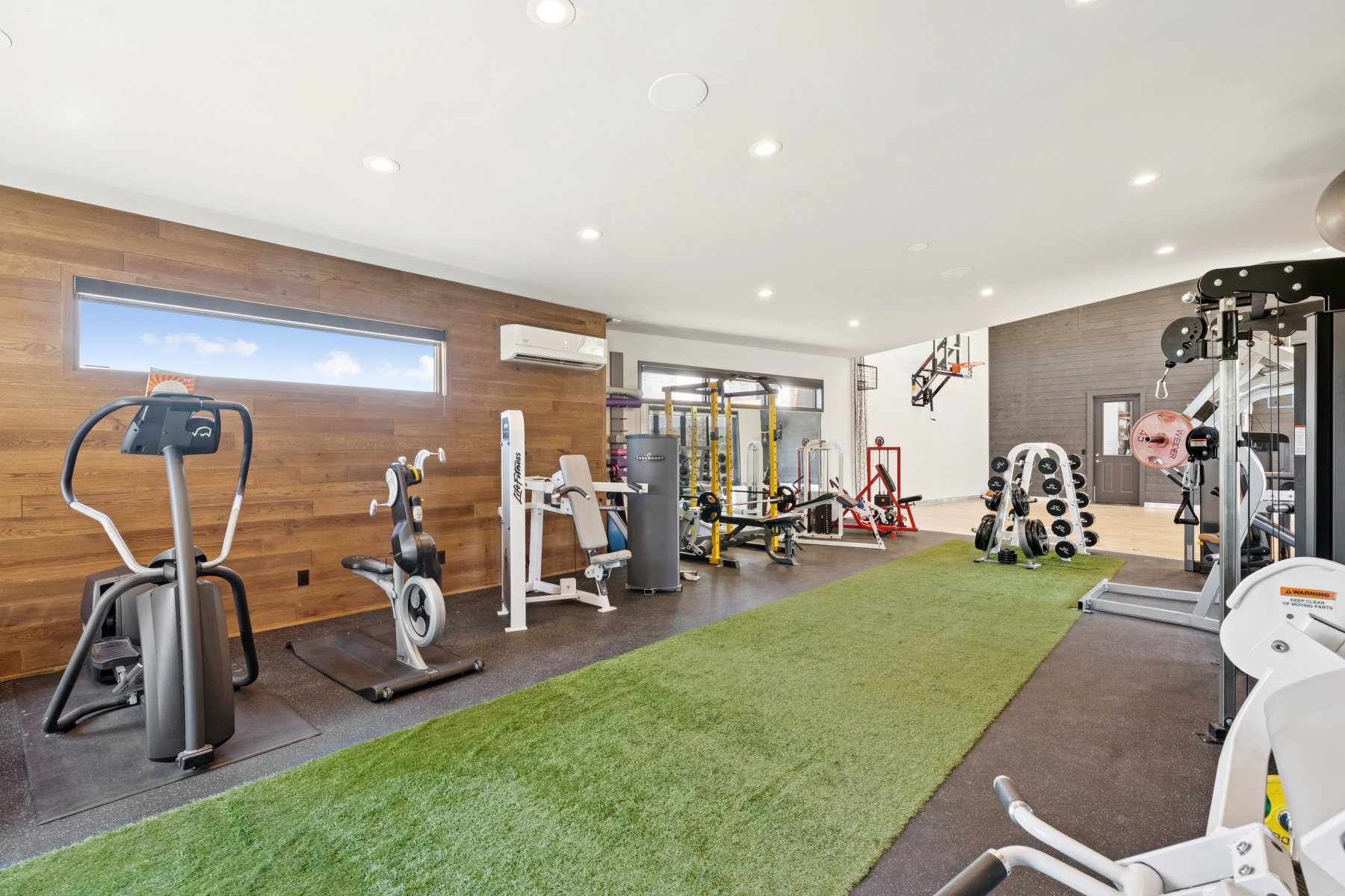 Dedicated fitness space featuring wood-finish wall paneling, a horizontal window, and recessed lighting