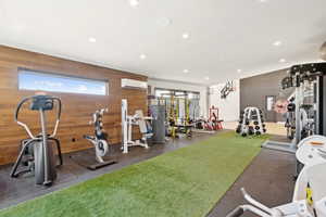 Dedicated fitness space featuring wood-finish wall paneling, a horizontal window, and recessed lighting
