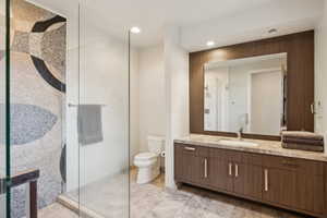Glass-enclosed shower with a decorative mosaic tile wall, a contemporary wood-finish vanity with an integrated sink, a large mirror, and recessed lighting