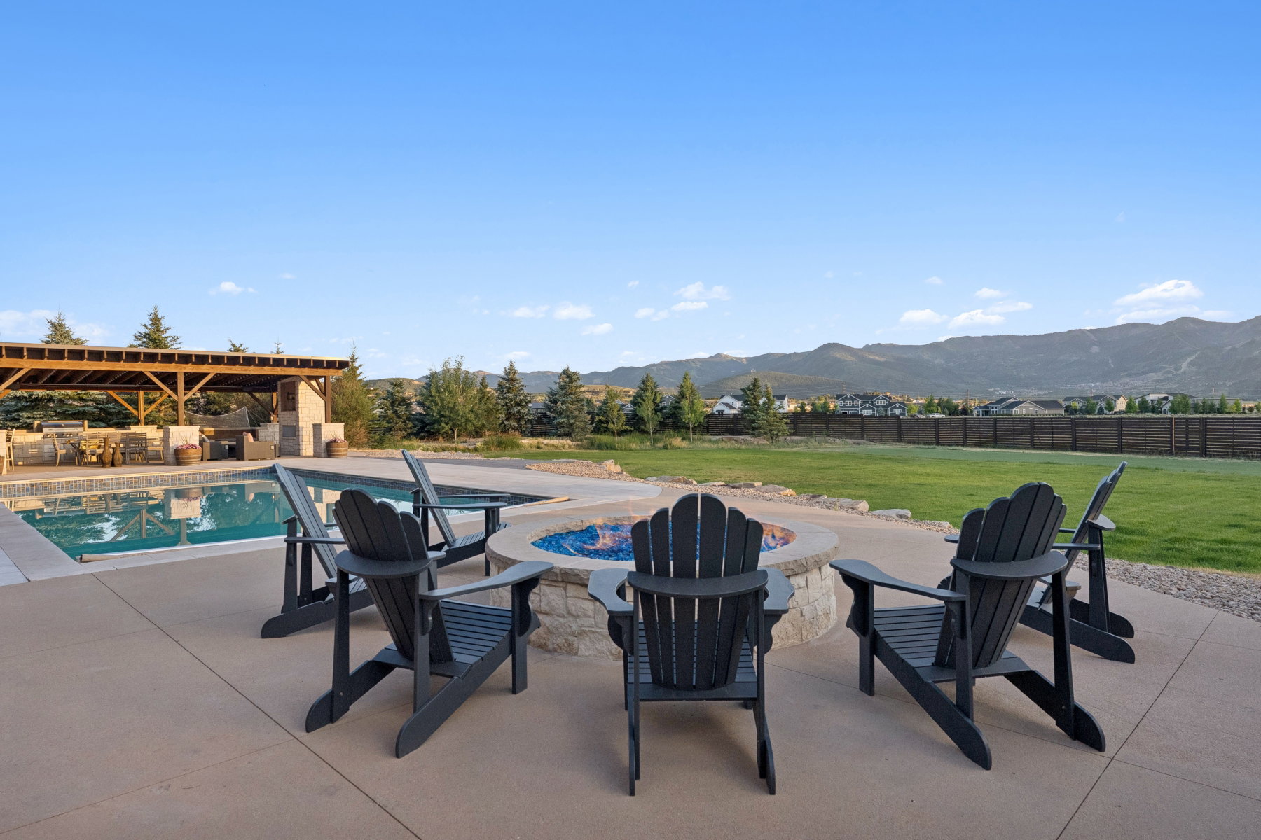 Outdoor living area featuring a stone-clad fire pit, swimming pool, and a timber-framed covered patio