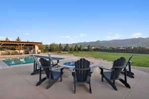 Outdoor living area featuring a stone-clad fire pit, swimming pool, and a timber-framed covered patio