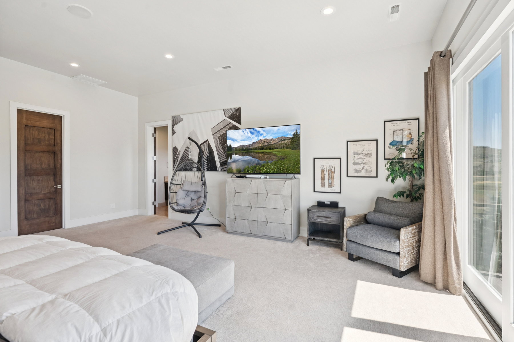 Spacious room featuring light-colored carpeting, recessed lighting, and a dark wood-finish door